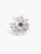 Silver-tone ring with red oval center stone, surrounded by purple and clear stones