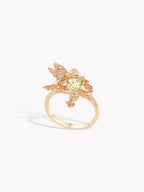 Gold hummingbird ring with yellow gemstone center and glittering wing details