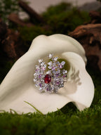 Silver-tone ring with red center stone and surrounding purple and clear pavé floral cluster