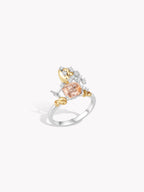 Test ring with silver band, peach center stone, and gold leaf side accents