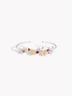 White gold gemstone bracelet with central gold motif and dangling floral details
