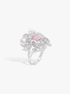 Floral branch ring with raised pink oval center stone and scattered clear diamonds