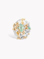 Gold gemstone ring featuring teal center oval with white sparkle stones and yellow details