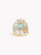 Gold wave ring with oval teal gemstone center and clear stones with yellow accents
