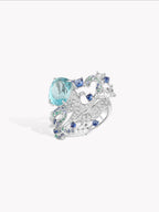 Silver ring with large oval aqua center stone and blue clustered stones, side view
