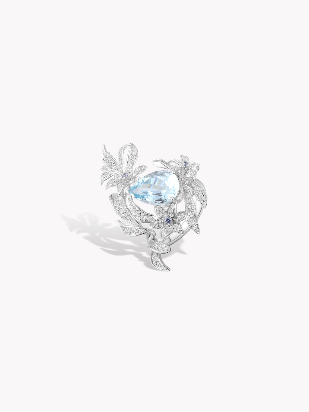 Silver floral ring with large aquamarine-blue oval gem, leaf shapes, and crystal stones