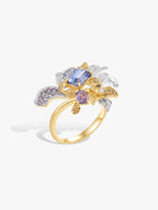 Gold iris ring with blue square center stone, purple side stones, prong-set sparkle