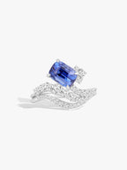 White gold ring with cushion-cut blue sapphire and diamond wave setting