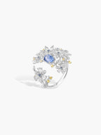 Floral branch ring with blue oval center stone, curved band, clear stones and gold-toned accents