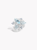 Snowflake twist ring showing band and oval blue center stone with sparkling halo