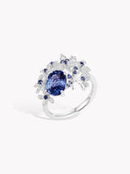 18K white gold ring with oval blue sapphire and halo of small gemstones