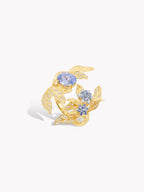 Gold-tone laurel leaf ring with round blue center stone and small light-blue accents