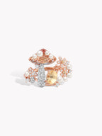 Rose gold-tone ring with pearls, blue center stone, and halo of clear gemstones