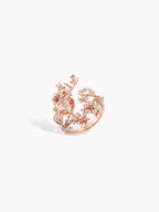 Rose-gold heart-shaped branch ring with pink-toned stone clusters and leafy details