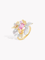 Floral ring showing oval pink center stone, clear pavé details, gold band and silver accents