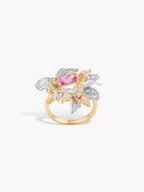 Oval pink gemstone ring with gold band, wrapped by gold and silver leaf motifs with clear stones