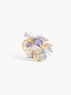 Gold and silver floral ring with oval blue gemstone center and clear pavé stones