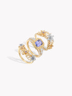 Gold-toned ring with purple sapphire center, split shoulders, and diamond-like stones