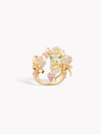 Gold-tone ring with large central light green stone and pink gemstone clusters