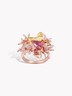 Gold-tone ring with pink gemstone centerpiece and sparkling pink stone halo