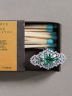 Close-up cluster ring with green center stone and pavé clear stone halo