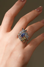 Cat sapphire ring on hand, oval blue center stone with green and white accents