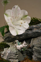 Cat pendant necklace with green gemstone clover and leaf charms, silver chain.