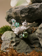 Cat pendant necklace with emerald-like green stones, butterfly and clover charms, silver chain.