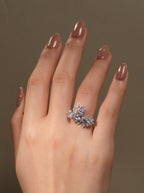 Pear-shaped pink diamond cluster ring with floral butterfly side stones on hand.