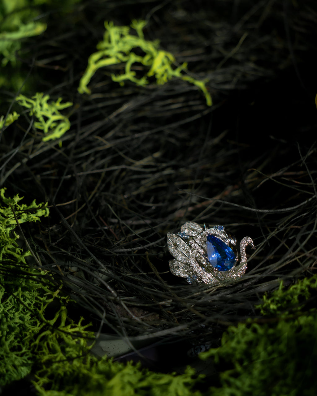 Swan motif ring with oval blue center stone framed by crystal pave details