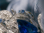 Sapphire swan ring close-up: oval blue center stone with diamond-like side stones
