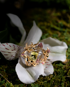 Gold-tone strawberry cluster ring on a white flower with pink and light green gemstones