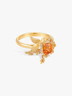 Gold-tone bird ring with orange center gemstone and sparkling diamond accents