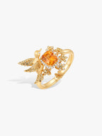 Gold-tone bird ring with orange oval center stone and diamond accents