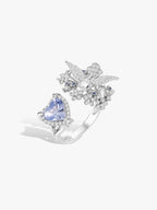 Open ring with heart-cut blue sapphire surrounded by white stone leaf clusters