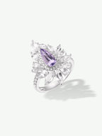 Purple marquise center ring with ornate halo and clustered clear stones on band