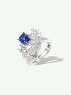 Sapphire blue gemstone ring with curved silver shank and sparkling rectangular halo