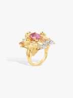 Gold-toned ring with oval pink gemstone, puppy charms, and white diamond accents.