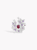 Silver-tone ring viewed from above with red center stone and surrounding purple and clear blossoms