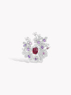 Silver-tone ring viewed from above with red center stone and surrounding purple and clear blossoms