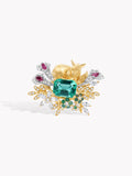 Gold ring with teal emerald-cut center, floral prongs, clear stones, and magenta gems