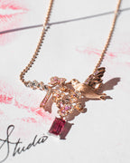 Rose-gold bird necklace with pink cherry blossom clusters and pink gemstone drop